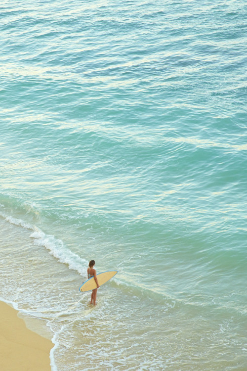 High angle view of Pacific Islander woman carrying surfboard on beach